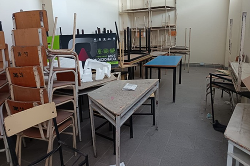 Sala de informática de primaria – antes de la adecuación (2024): aula con mobiliario antiguo y desordenado, mesas y sillas apiladas, ausencia de equipos de cómputo funcionales y condiciones limitadas para el desarrollo de actividades pedagógicas con estudiantes de preescolar y primaria.