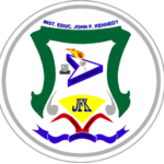 Escudo de la Institución Educativa John F. Kennedy. Tiene forma de blasón con borde blanco y contorno gris. En la parte superior aparece el nombre de la institución en letras azules. El interior del escudo tiene franjas verdes a los lados y una base amarilla. En el centro se observa un libro abierto con una antorcha, símbolo de conocimiento y formación. En la parte inferior aparecen las letras “JFK” en color verde sobre fondo amarillo, y debajo una cinta ondulada con los colores de la bandera de Colom